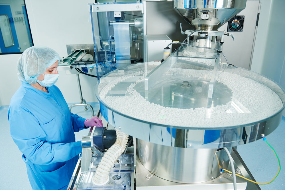 Donna davanti ad un macchinario di produzione farmaceutica